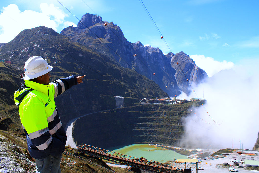 Transnational mining companies pull in 'super' profits, but at what cost? (Wikimedia Commons) A worker at a mining site points to the low-hanging clouds.
